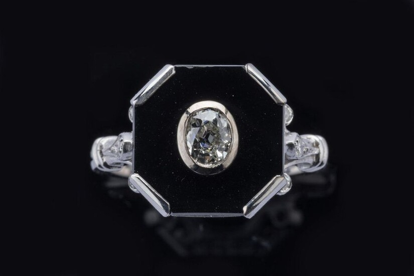 RING in 750 thousandths white gold, decorated with an old cut diamond on a background of onyx surrounded by six brilliant-cut diamonds. The shoulder of the kitten in fleur-de-lys. Finger size: 54. Gross weight: 5.3 g. Approximate weight of the central...