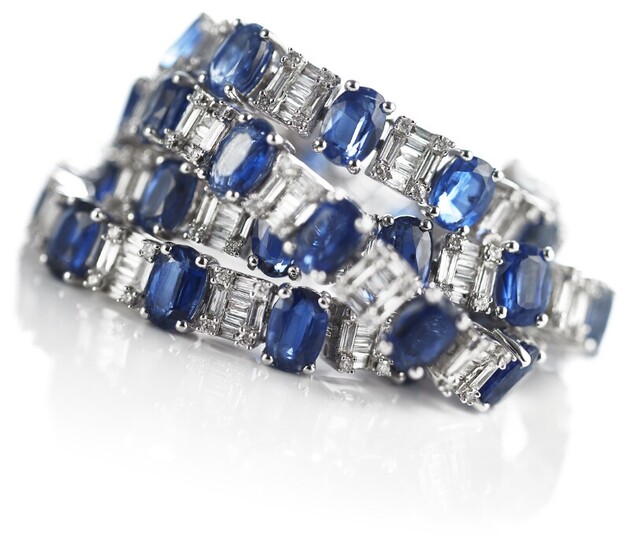 A sapphire and diamond bracelet set with numerous oval-cut sapphires and numerous brilliant and baguette-cut diamonds, mounted in 18k white gold.