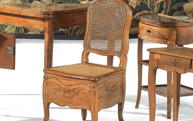 Chaise de commodité en bois naturel sculpté à décor de fleurettes. Assise et dossier cannés....