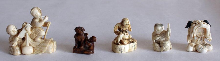 JAPAN, late 19th century. Lot of five NETSUKES and GROUPS, four in ivory, woman smoking pipe and sawyer, dog figure, child playing drum (missing) and child with a Fô dog mask, and one in carved wood carving figure of a sitting Fô dog.5x 6 x 3 cm, H. 4...