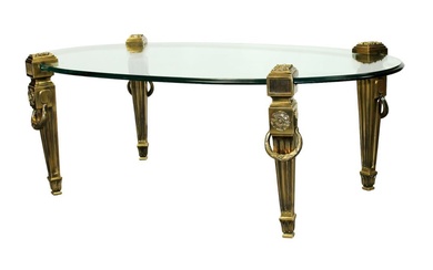 Polished bronze coffee table with oval glass top in the...