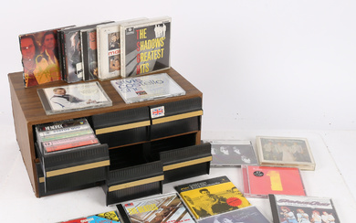 A COLLECTION OF CDS AND TAPES WITH A STORAGE UNIT.