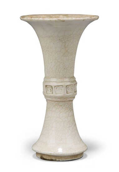 A Chinese porcelain white-glazed small vase, gu, 18th century, the raised central section decorated with band of stamped key-fret design, covered in an allover white glaze suffused with brown crackles, 11cm high