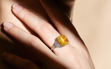 A YELLOW SAPPHIRE AND DIAMOND RING set with an octagonal mixed cut yellow sapphire of approximate...
