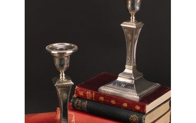A pair of Edwardian silver square table candlesticks, in the...