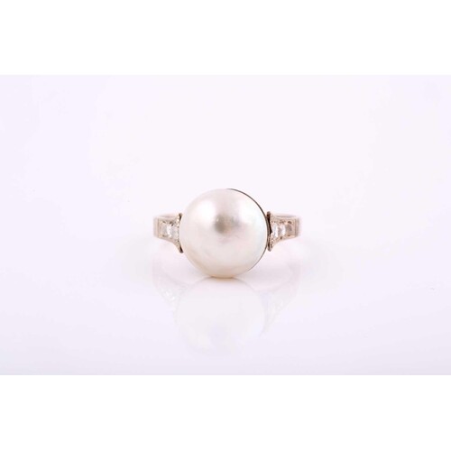 A ring set with a central Mabe pearl with diamond chips on t...