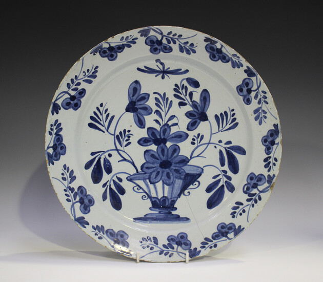 An English Delft charger, 18th century, painted in blue with a vase and flowers, the rim similarly d