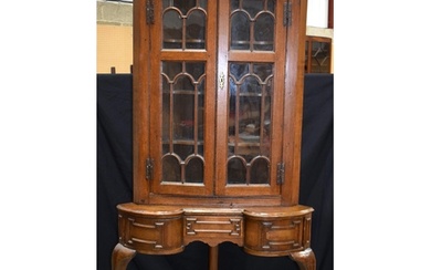 An Oak glazed door corner cabinet on a a stand with one cent...