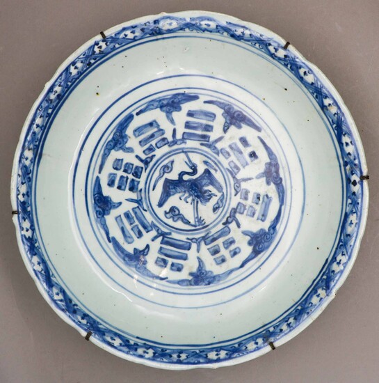Grand plat festonné en porcelaine à décor de grue, nuées, trigrammes et motifs stylisés en...