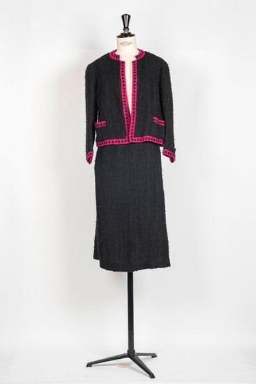 97. Chanel, haute couture. Circa 1965.Tailleur en lainage noir orné sur tous les bords d’un galon en fine laine reprenant le fuchsia de la doublure. T 36 (env.). (Usures et salissures).