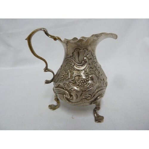 A George II silver cream jug, of baluster form embossed with...