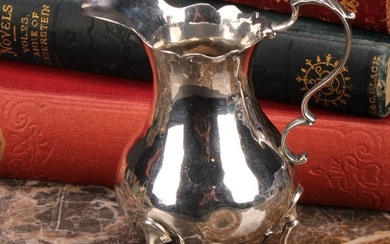 A George III silver baluster cream jug, wavy rim, acanthus-c...
