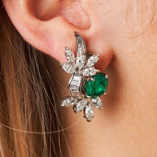 A PAIR OF EMERALD AND DIAMOND EARRINGS each set with an oval cut emerald accented by a spray of
