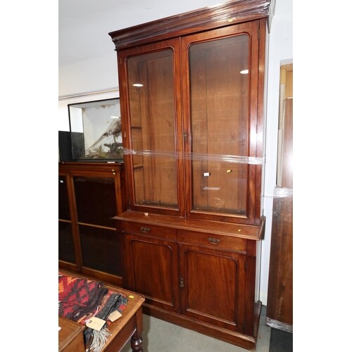 A late 19th century walnut bookcase, the glazed upper sectio...