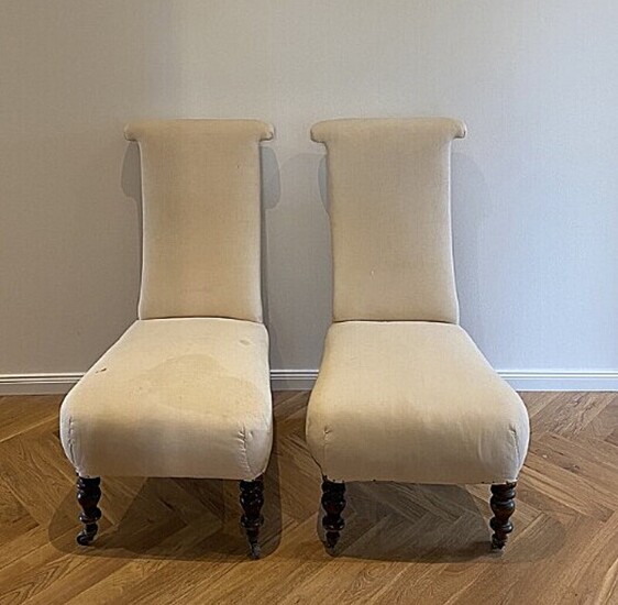 A pair of chairs upholstered in light fabric, turned dark wooden legs and brass wheels. Late 19th century. H. 100. (2)