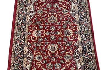 A red ground floral decorated rug with blue and cream...