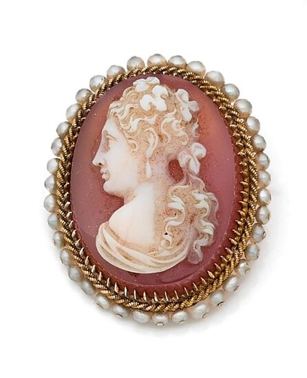 Oval brooch adorned with a white agate cameo on an orange background with a woman's bust in profile, the yellow gold setting surrounded by a twist and a row of fine stitched pearls. Late 19th century. Pin in 14 k gold. Gross weight 16 g. Dim. 3.5 x 3...