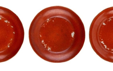 Three Chinese monochrome iron-red saucer dishes, 18th century, of shallow ogee form, 12cm diameter 十八世紀 鐵紅釉盤三件