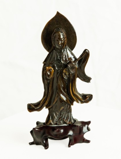 A Chinese Tiger Eye carving of the Goddess of Mercy with aura on a carved wooden stand, total height 20cm