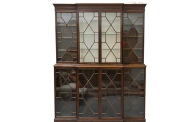 A George III style mahogany breakfront bookcase, the dentil moulded and fluted cornice over two rows