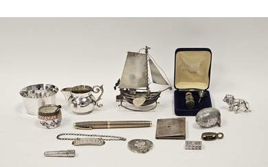 A collection of silver and white metal objects, including an...