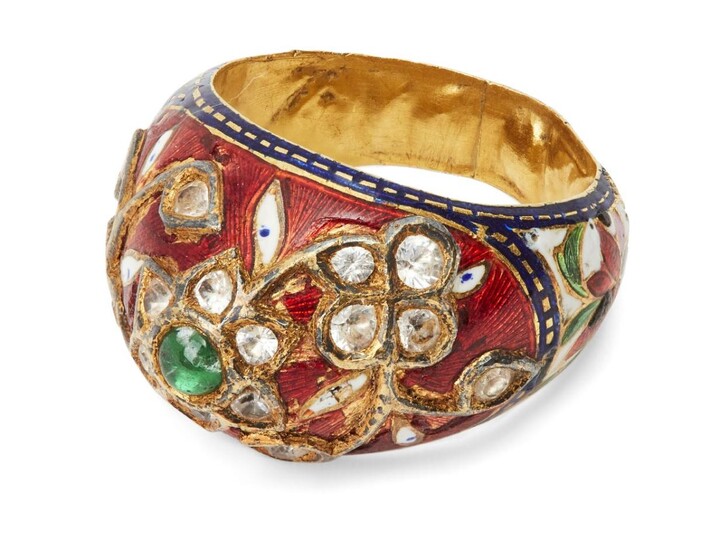 A diamond-set enamelled gold bombe ring, India, 19th century, the bezel set with a flower set with diamonds and central emerald, further flowers set with diamonds, on a red enamel ground with blue border, the shoulders with enamel flowers on a...