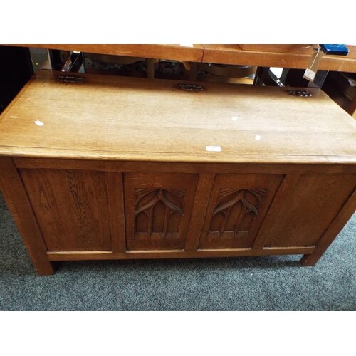 An oak coffer with arch window carved panels