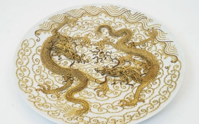A Chinese gilt-metal mounted porcelain plate, first half 20th century, embossed overall with two dragons amid scrolls, 33cm diameter