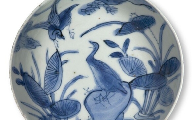 A Chinese porcelain blue and white kosometsuke dish, Tianqi period, painted with a bird perched atop a rocky outcrop with large lotus blooms emerging from the surrounding water, 13.5cm diameter Provenance: with paper collection label to base that...