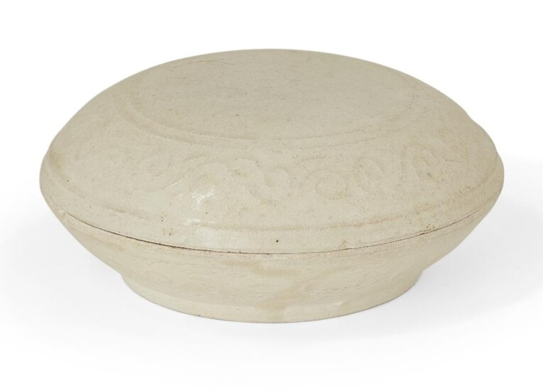 A Chinese white glazed porcelain circular box and cover, Yuan dynasty, the cover and base moulded with a band of scroll motifs, 10.5cm diameter 元 德化白釉印花卷草紋蓋盒