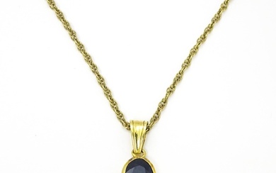 A yellow metal pendant set with central sapphire on a 9ct go...