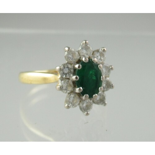 An emerald and diamond ring. The oval emerald approx 6x4.5m...