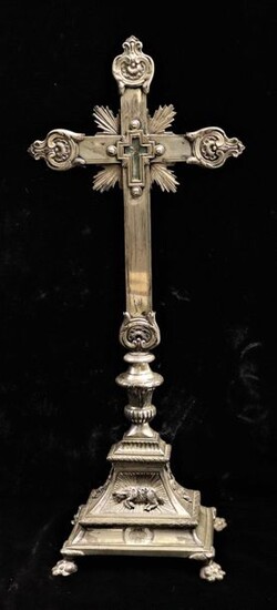 Silver staurothec cross, radiating ends decorated with acanthus leaves. It rests on a curved rectangular silver bronze base with four claw feet, decorated in bas-relief with the Pascal lamb.