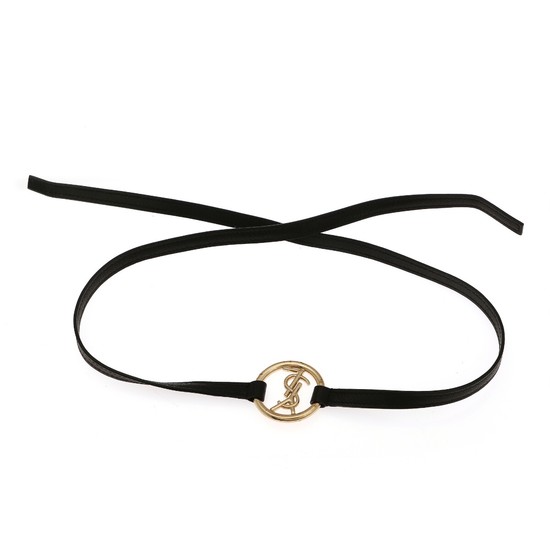 Yves Saint Laurent: A gold coloured “YSL” pendant with black leather cord. L. approx. 83,5 cm. Pendant diam. app. 3,6 cm.